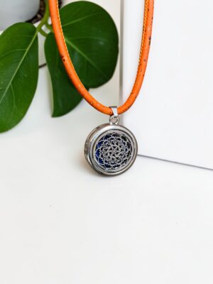 Pulseira Vahani Mandala em prata com fundo de cortiça laranja. Detalhe da geometria sagrada da mandala em metal sobre textura natural de cortiça para aromaterapia Swaminah.